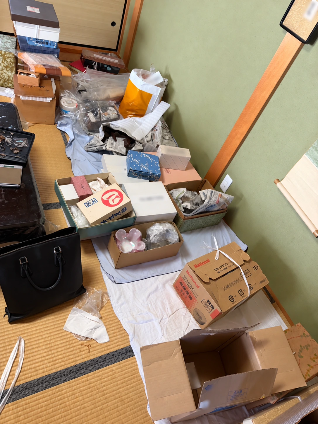 整理費の精算の相談準備：畳の部屋の壁際に箱入りの品、バッグ、小物、包装紙が置かれた様子