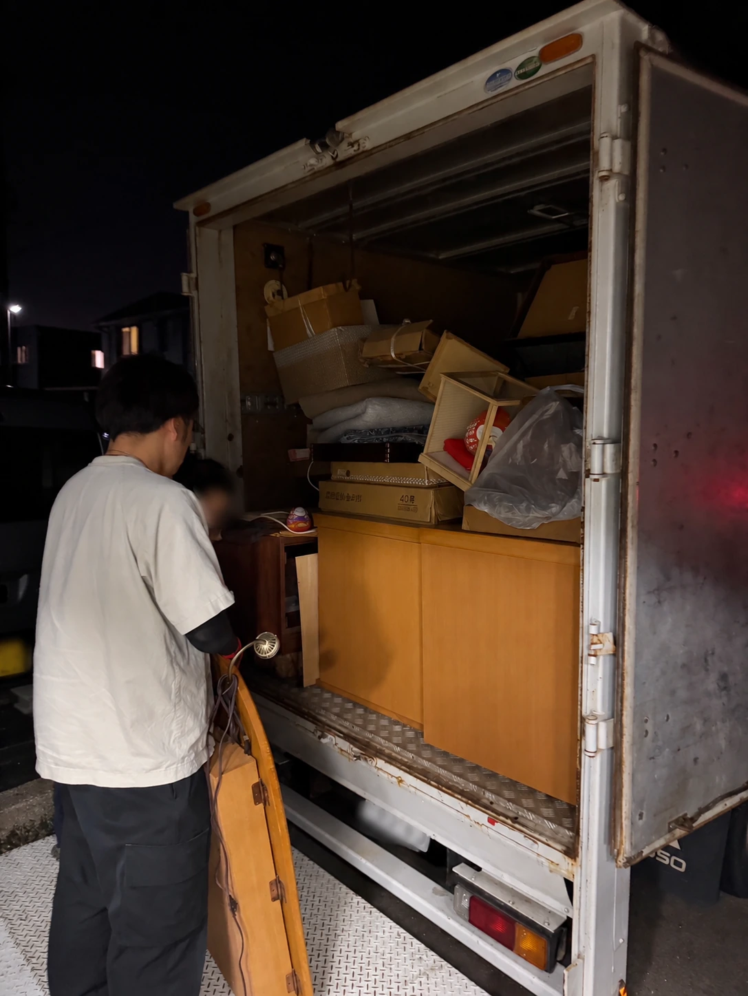 雨の日の片付けの相談準備:家具や箱を積んだトラックの荷室のそばに人物がいる様子